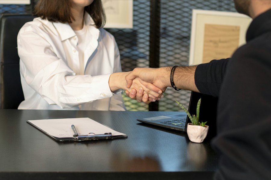 Two professionals shaking hands across a desk